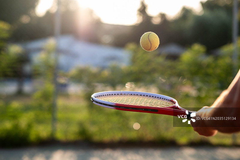 手在日落时打网球图片素材