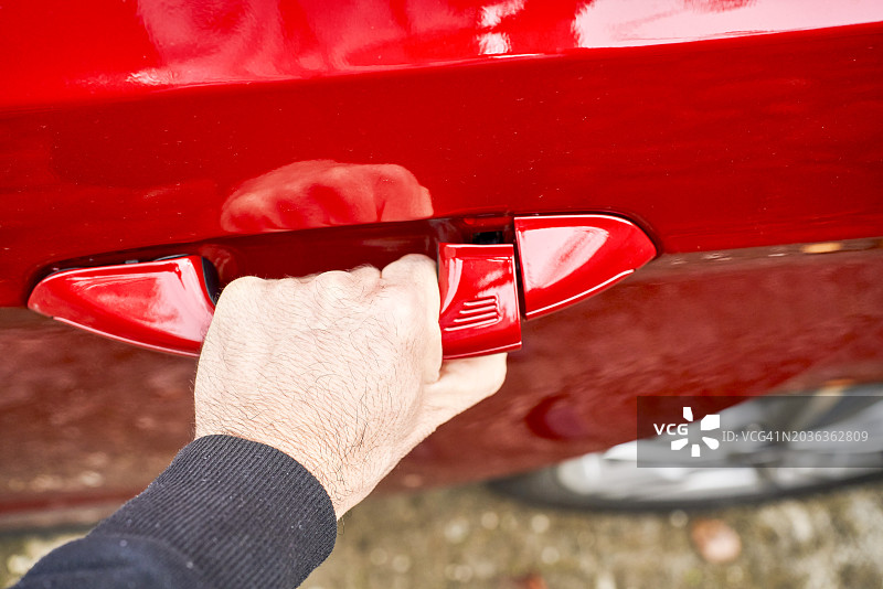 鲜红色车门，一名男子的手放在门把手上图片素材
