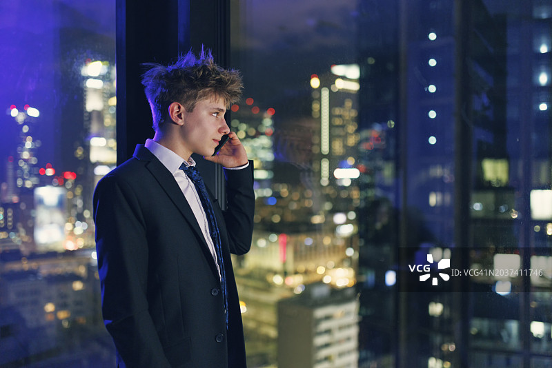 少年商人夜晚打电话俯瞰城市图片素材