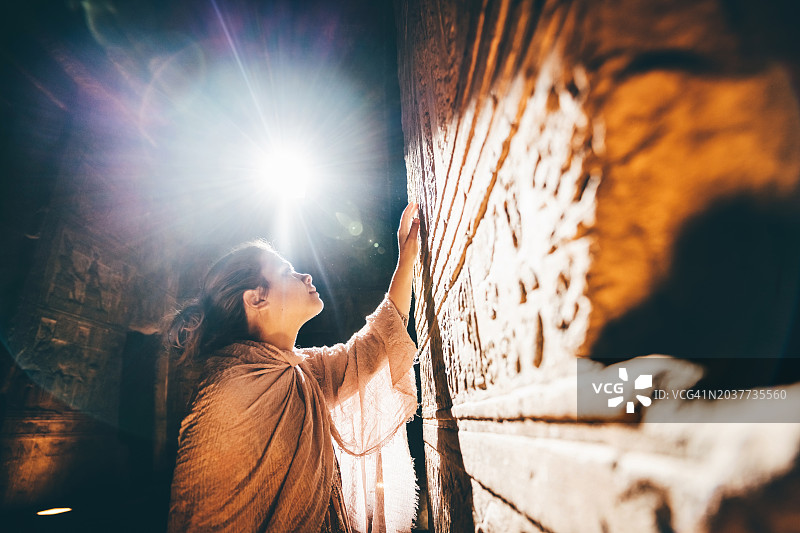 女人在美丽的光线下探索埃及的古代寺庙图片素材