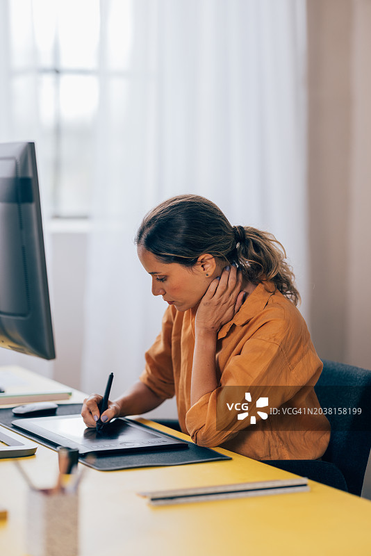 在现代办公室使用绘图板的专注女设计师图片素材