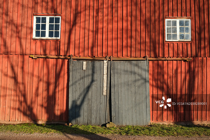 红色木制谷仓外墙，带两扇窗户和一个大门图片素材