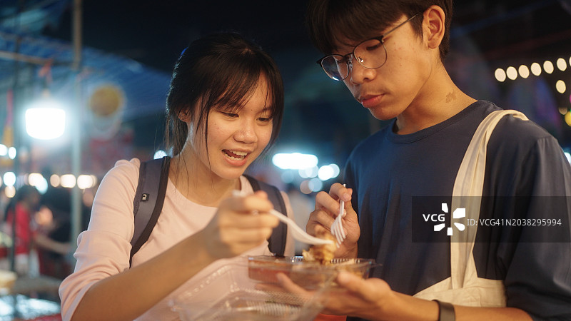 亚洲青少年在夜市吃街头小吃图片素材