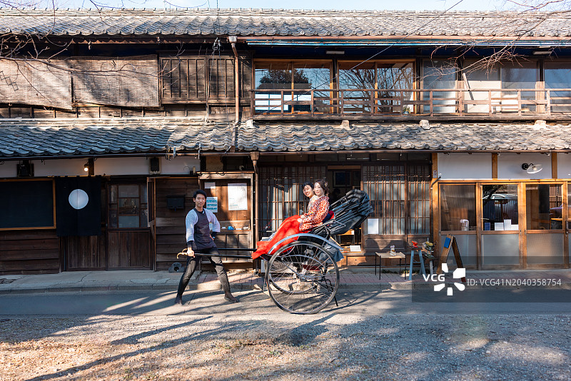 穿着和服/袴的女性游客在日本传统城镇乘坐人力车图片素材
