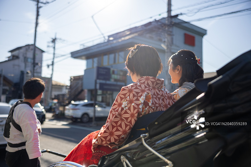 在日本传统小镇，穿着和服/袴的女性游客乘坐人力车图片素材
