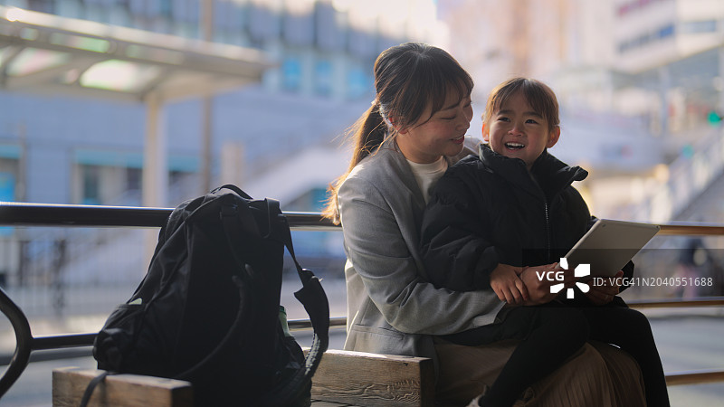 在巴士站等车时与女儿一起工作的女商人图片素材