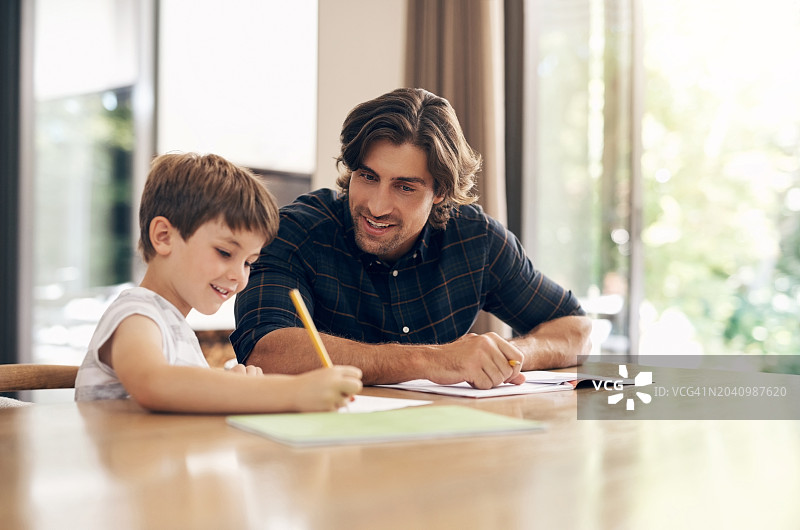 快乐聪明的男孩在家在爸爸的帮助下做作业图片素材