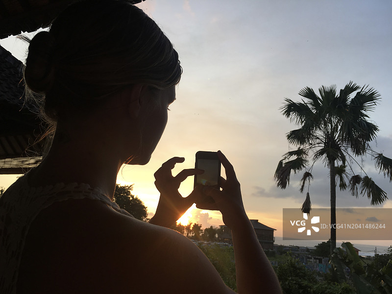 年轻女子在热带环境中拍摄日出图片素材