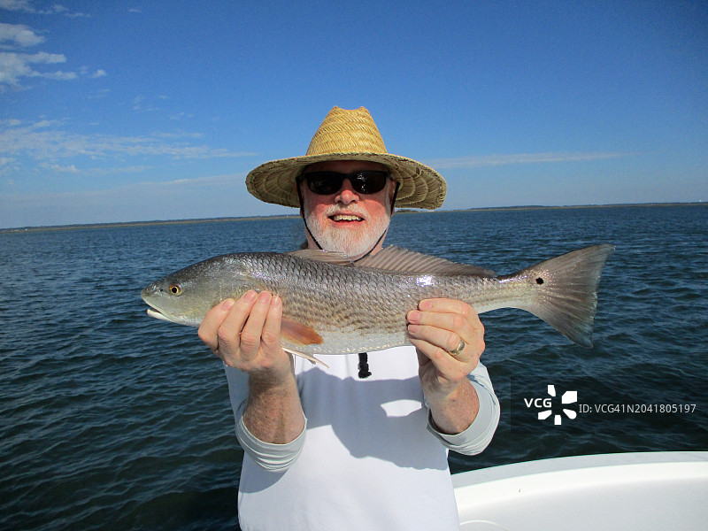 男人戴着草帽和红鱼图片素材