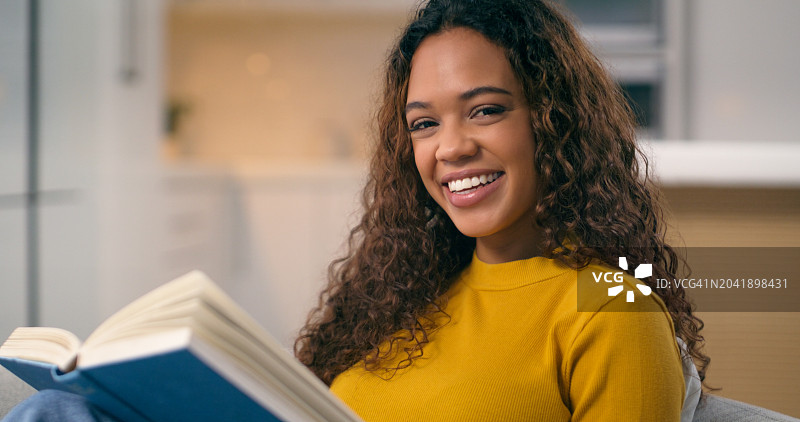 快乐的女人在客厅的沙发上读书，在模糊的背景下进行幻想、学习和教育。大学生，微笑并学习故事，在休息室里获取知识和准备考试图片素材
