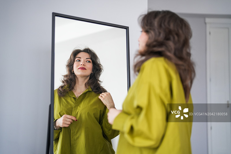 棕发美女在客厅的镜子前欣赏自己图片素材