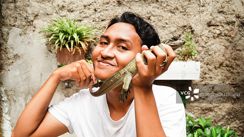 亚洲男人手持帆鳍蜥并微笑图片素材
