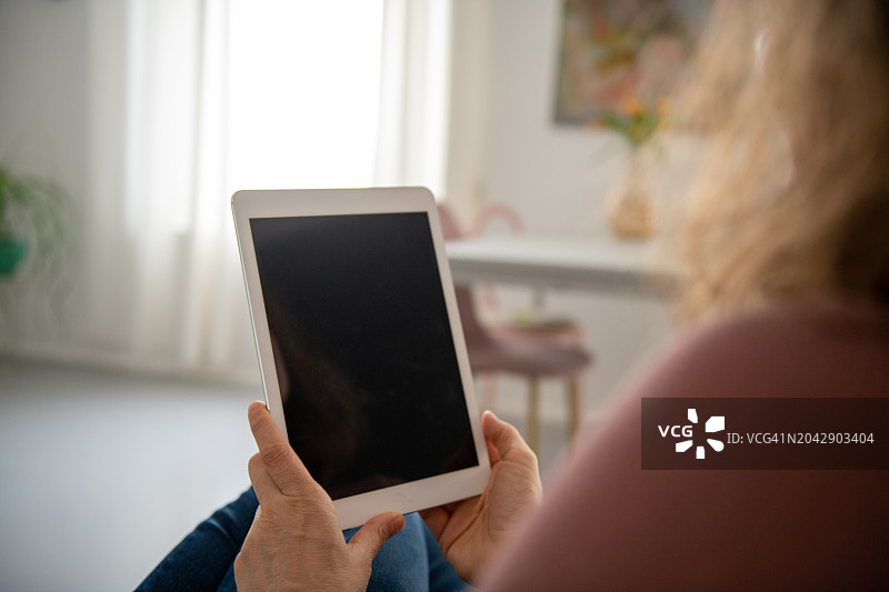 女士在沙发上使用平板电脑图片素材