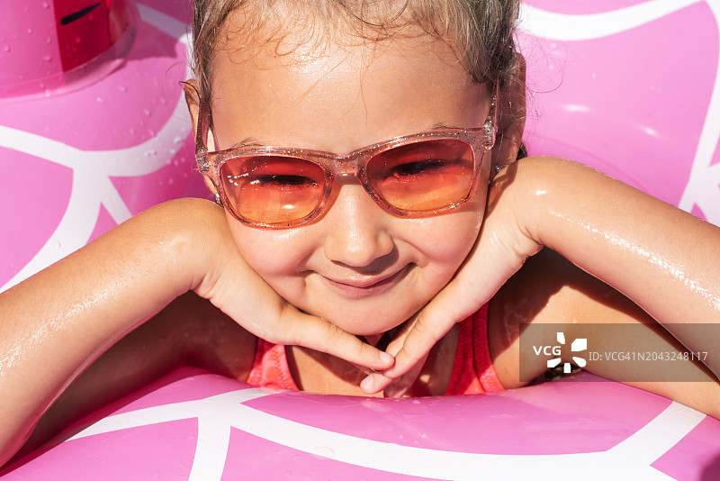 在游泳池里带着充气游泳圈的女孩。夏天。休息。假日。一个孩子学习游泳。小女孩的肖像。孩子们的消遣。健康和运动的生活方式。图片素材