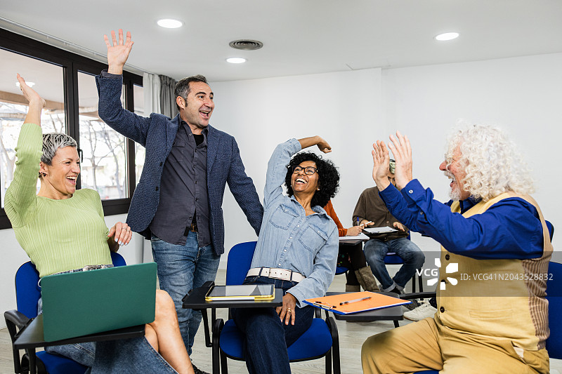 老师和中年学生在团队击掌后欢呼雀跃图片素材