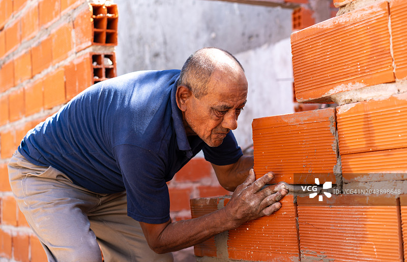 在建筑工地砌砖墙的年长男人图片素材
