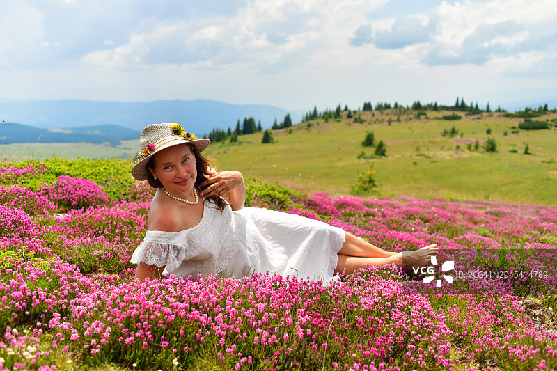 在开满粉红色花朵的草地上放松的美丽孕妇图片素材