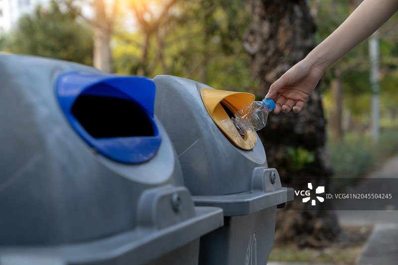 在公园里，手将塑料瓶扔进垃圾箱图片素材