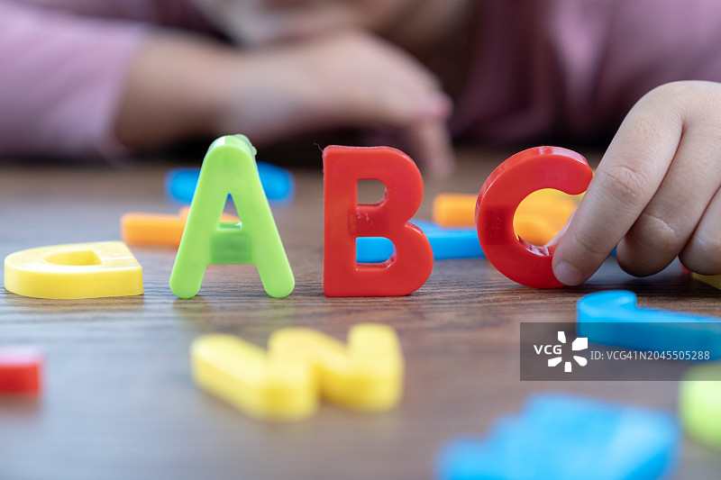 女孩在玩英语字母。图片素材
