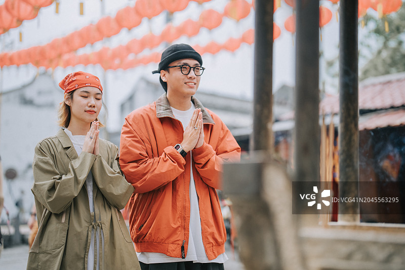 中国亚洲游客夫妇在槟城岛中国寺庙前祈祷，庆祝中国新年元宵节图片素材
