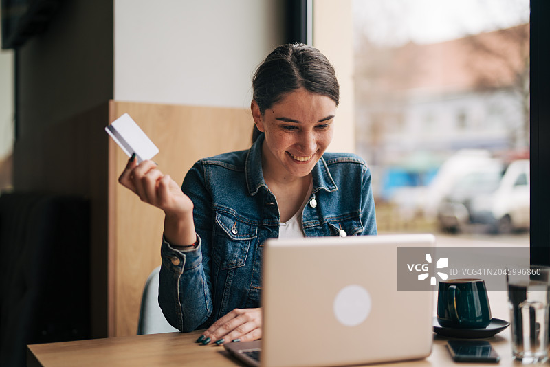 在咖啡馆用笔记本电脑在线购物的女人图片素材