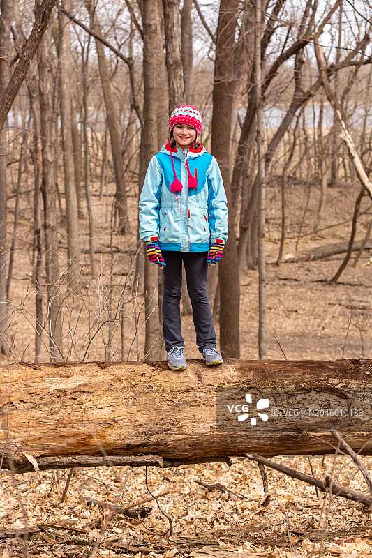 两个女孩站在春天树林里的大树干上图片素材