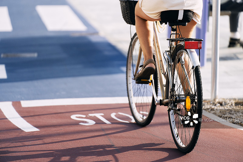 女人在阳光明媚的自行车道上骑自行车（腰部以下视角）图片素材