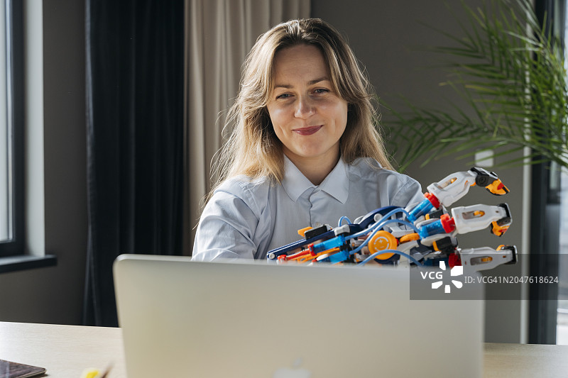 微笑的工程师在办公室通过笔记本电脑在视频通话中展示机器人手臂项目图片素材