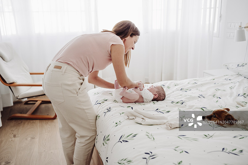 女人在家中床上为女儿换衣服图片素材