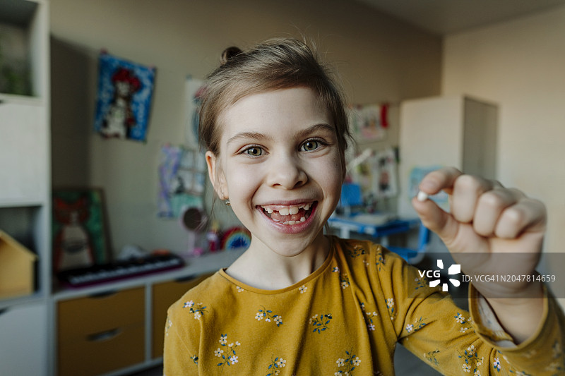 快乐的女孩在家拿着断掉的牙齿图片素材