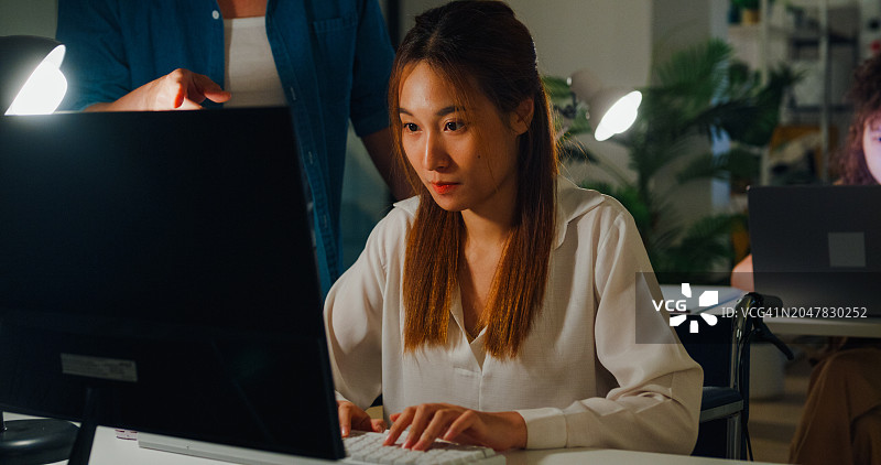 亚洲男经理指责坐轮椅的年轻女员工，暗示夜间办公室工作场所气氛紧张。ESG可持续商业办公室图片素材