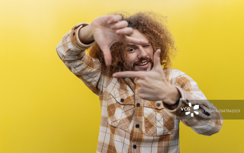 男人在黄色墙壁前用手指做框架图片素材