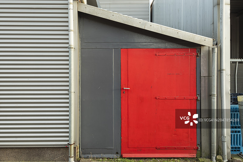 灰色墙面上的一扇红色钢门图片素材