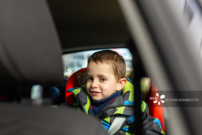 坐在汽车安全座椅上微笑的小男孩图片素材