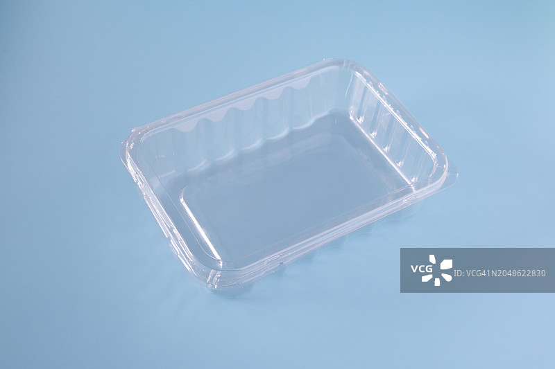 蓝色背景上的单个透明塑料食品容器图片素材