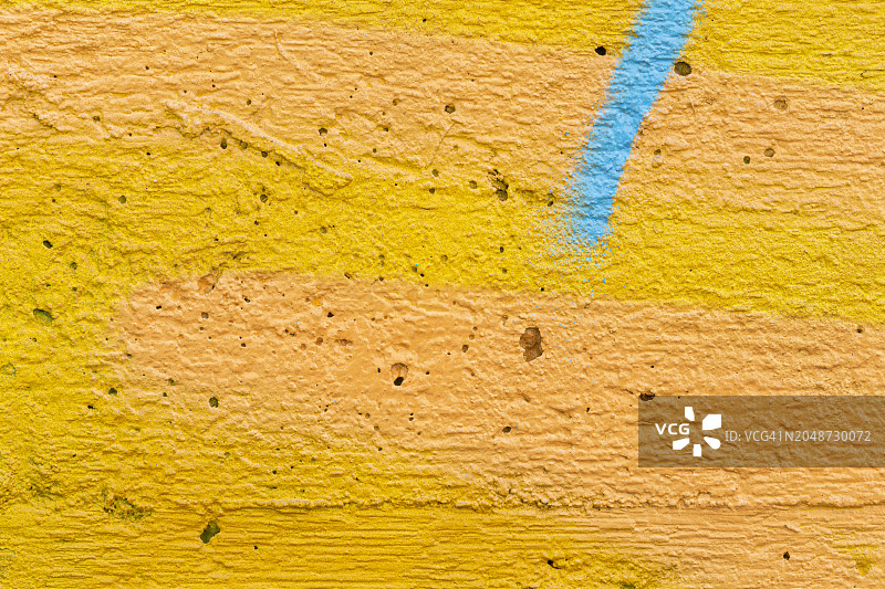 喷绘亮黄色和橙色墙壁与蓝绿色条纹的微距特写图片素材