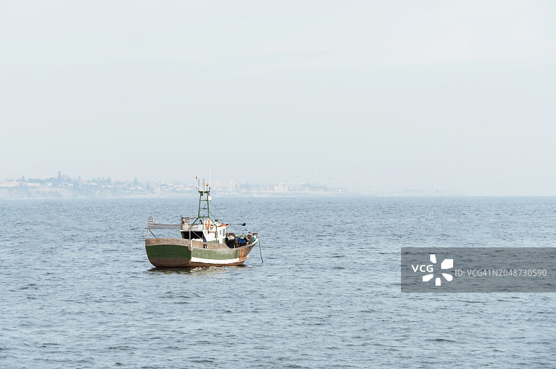 停泊在海湾的生锈绿色旧渔船图片素材