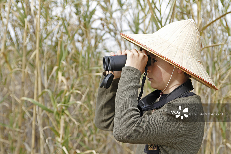 男孩在森林里用双筒望远镜观察图片素材