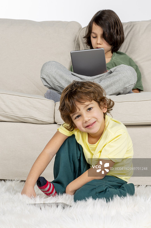 小男孩在地毯上玩平板电脑图片素材