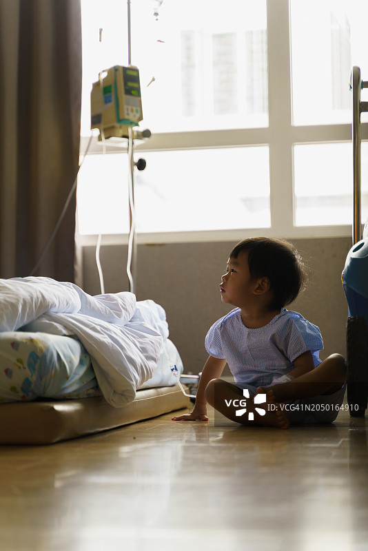 生病的小男孩在医院地板上接受静脉滴注的剪影图片素材