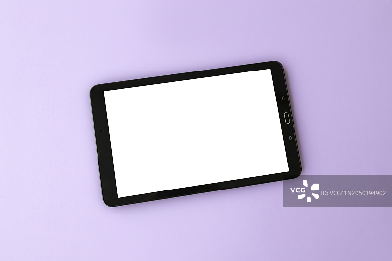 在时尚薰衣草色表面上的带白色屏幕的平板电脑图片素材