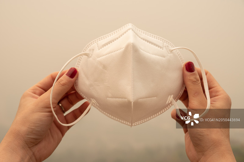 手持口罩预防空气污染的局部照片图片素材
