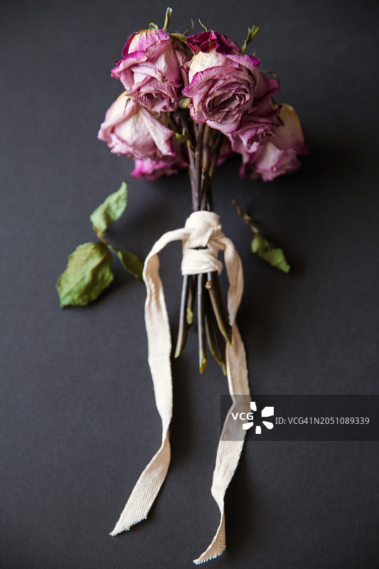 黑色背景上的丝带干玫瑰小花束，留白图片素材