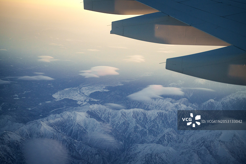透过飞机舷窗，清晰可见下方的雪山轮廓图片素材