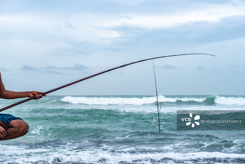 当地渔民在斯里兰卡科加勒海滩上进行高跷钓鱼的局部照片图片素材