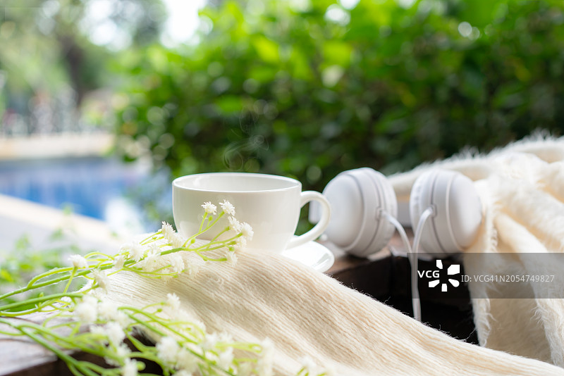 热咖啡与耳机木桌泳池绿色自然背景图片素材