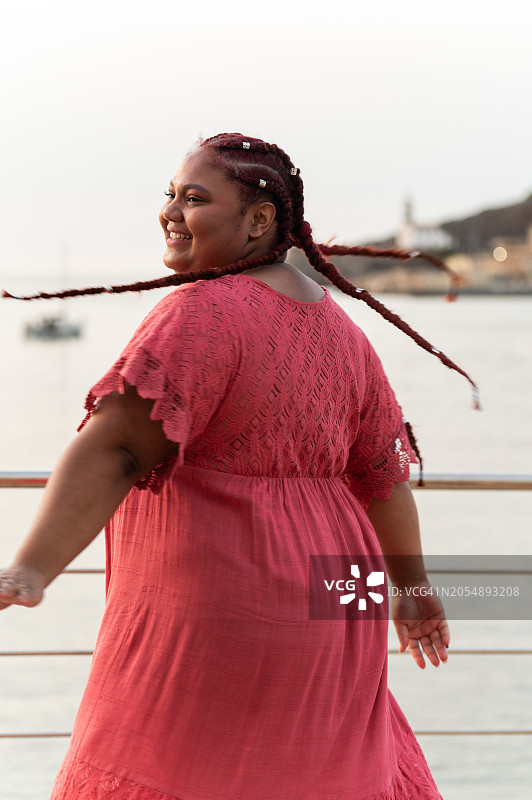 身穿粉色长裙的超重非洲裔女人高兴地摆姿势拍照图片素材