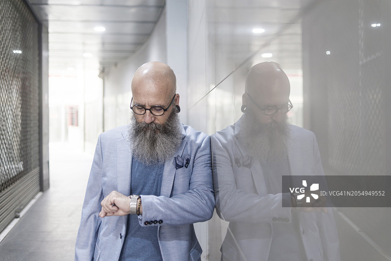 在走廊里查看手表的年长胡须潮人图片素材