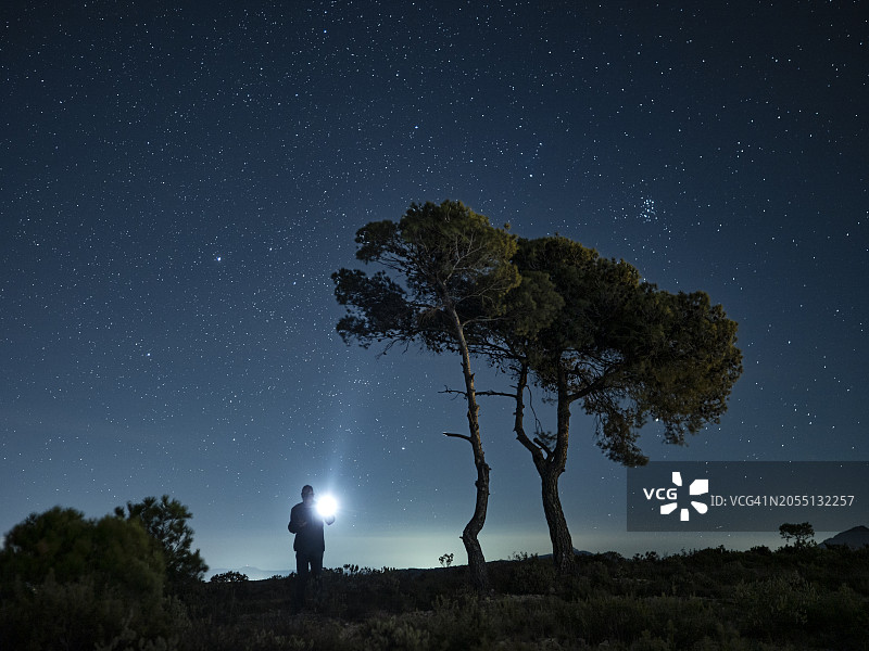 夜晚迷路登山者手持手电筒的轮廓图片素材