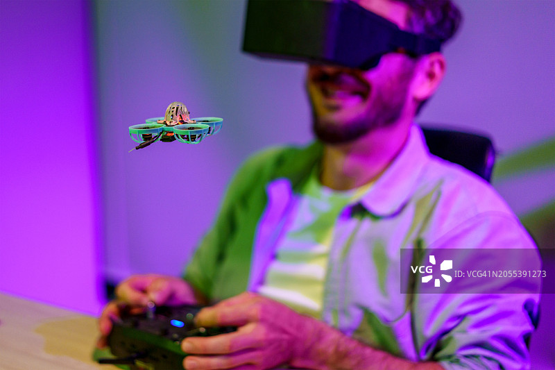 男人在家戴VR眼镜用遥控器操控小型无人机图片素材
